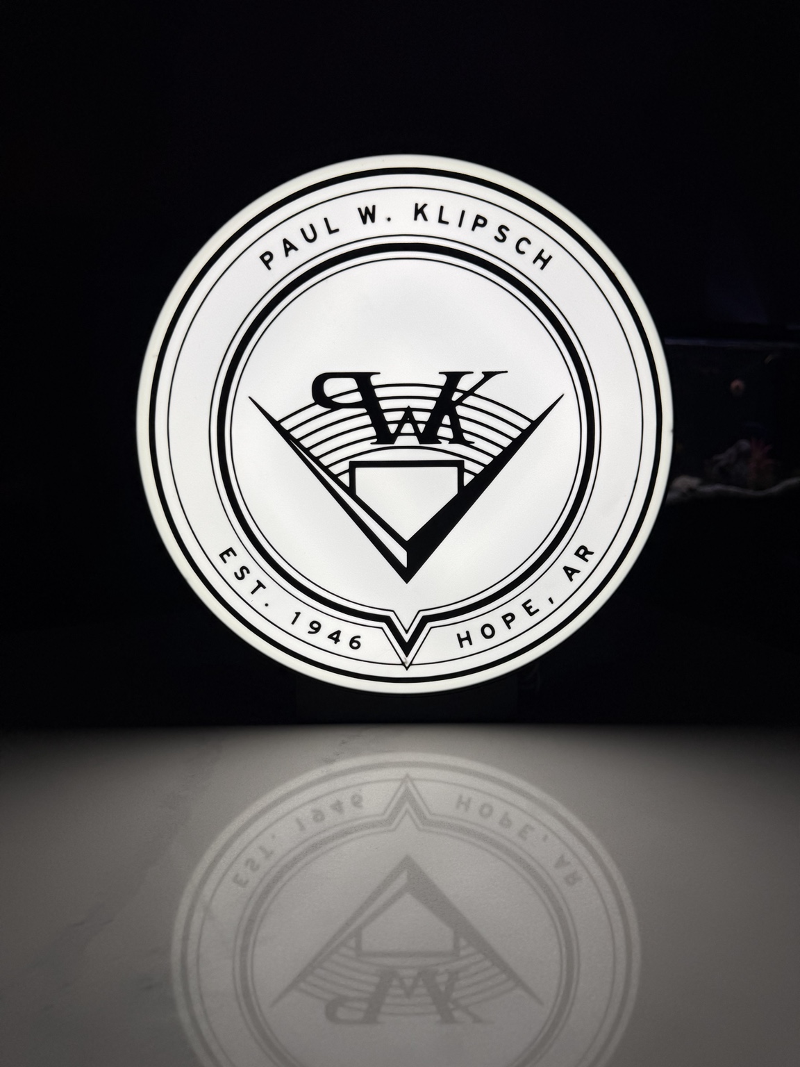 Circular white Paul W. Klipsch lightbox with black emblem
