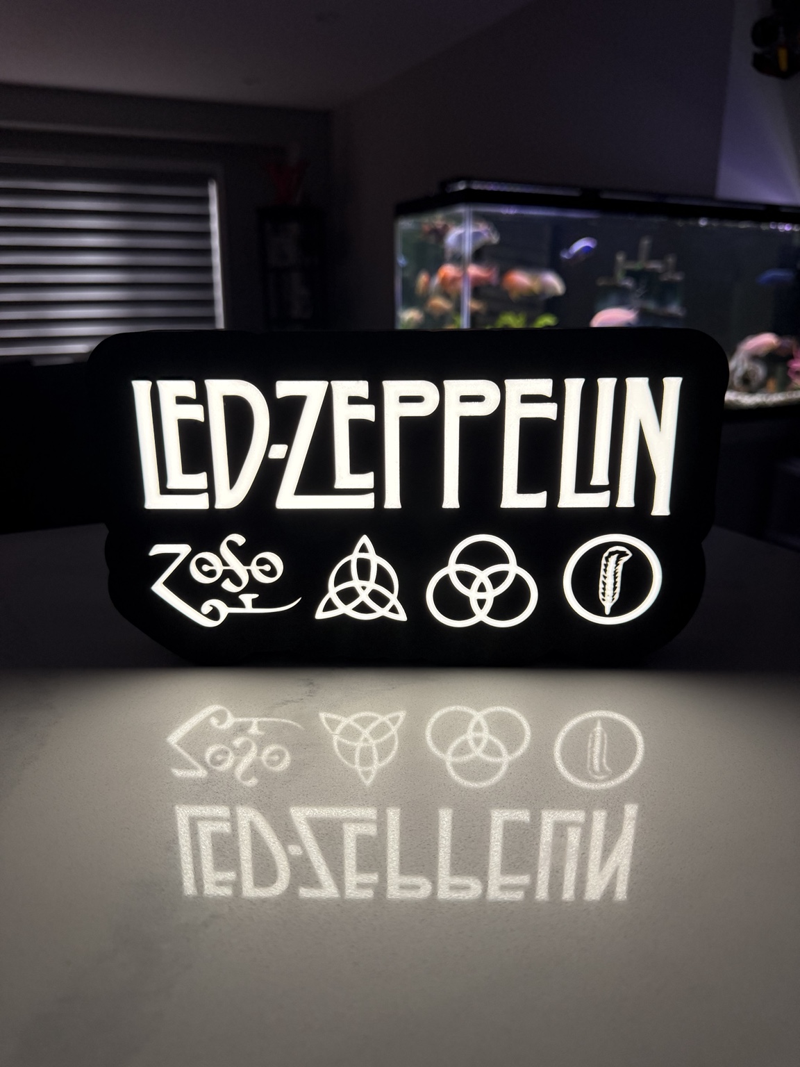 White Led Zeppelin lettering and symbols glowing against a black lightbox
