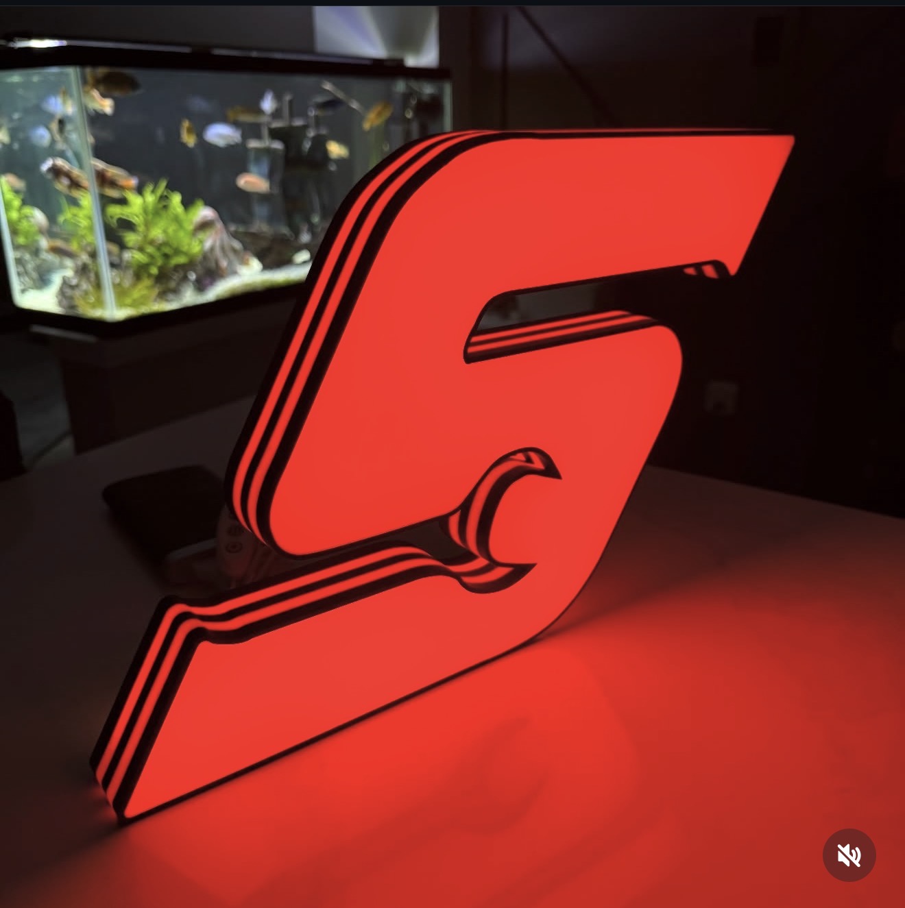 Sculptural red illuminated emblem shown from an angle