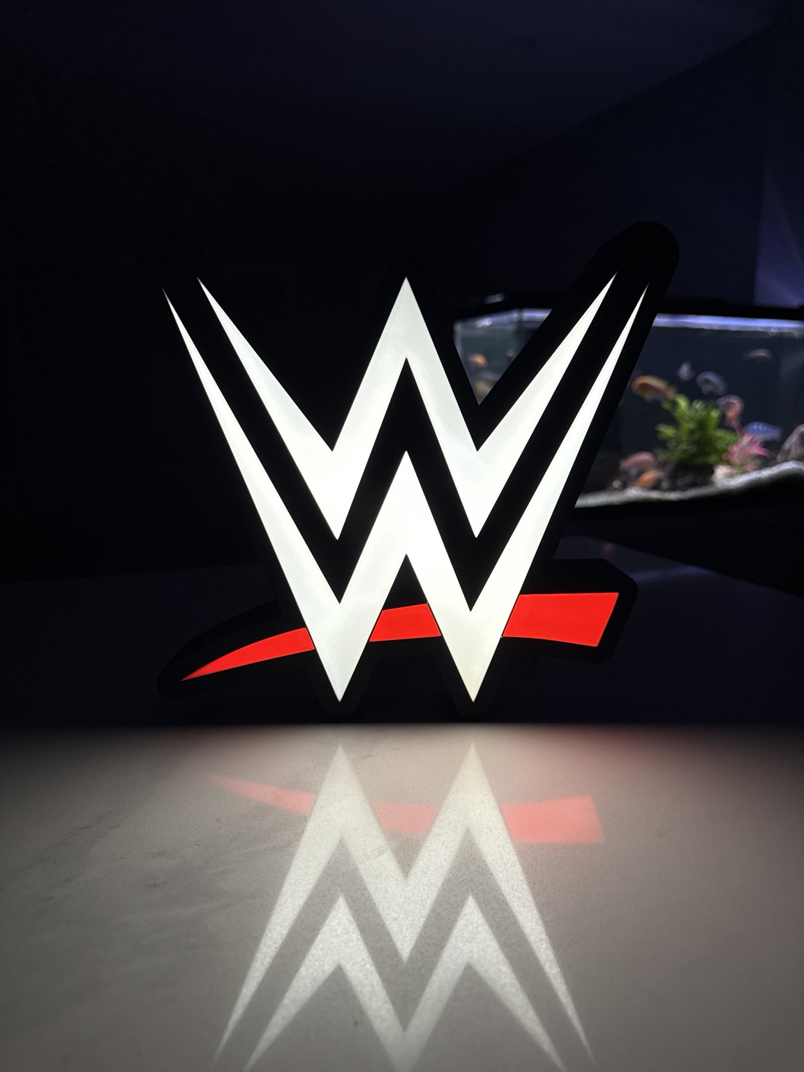 White WWE emblem with red accent illuminated as a sculptural lightbox
